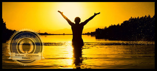 Achieving happiness through positive action. A person standing in the sunset with arms lifted in victory. A Flourishing Life Society Article header