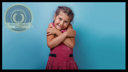 A little girl in a red dress, giving herself a hug. A Flourishing Life Society article on being kind to yourself.