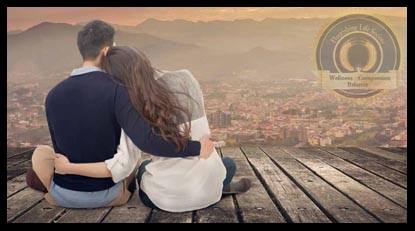 A young couple sitting on a wooden platform looking down on a city  in the valley beneath them. A Flourishing Life Society article on Building Strong Relationships