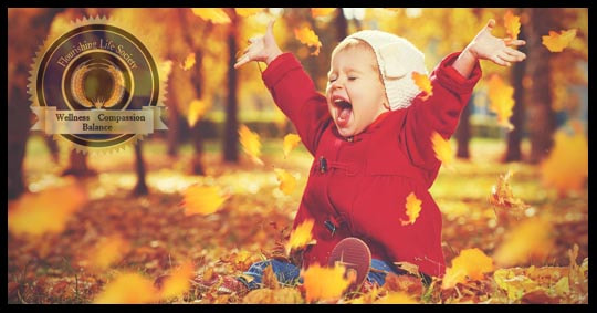 A Young child joyful playing in autumn leaves. A Flourishing Life Society article on emotional reactions to life experience.