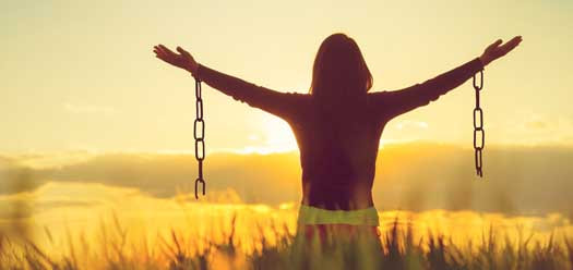 Woman freed from chains looking into sun. Mindfulness article at Flourishing Life Society