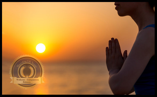 A woman in the namaste pose with an ocean sunset in background. An article on the origins of Namaste