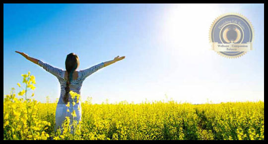 Woman in flower patch with arms raised in joy. An article on personal acceptance