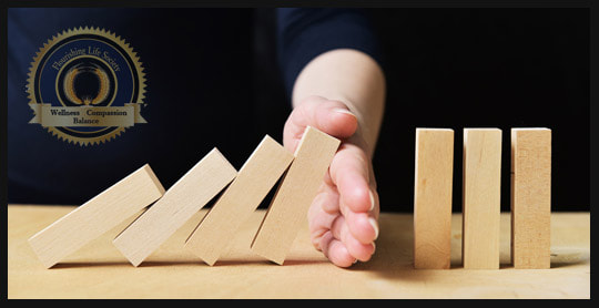 Hand stopping large falling dominoes. Flourishing Life Society article on addiction.