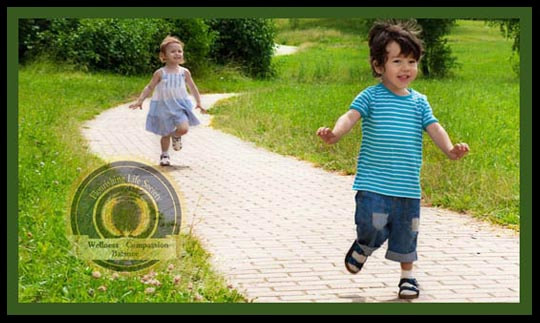 A little girl chasing a little boy down a path in a park. The Pursuit of Happiness. Finding happiness through balanced living. A Flourishing Life Society article.