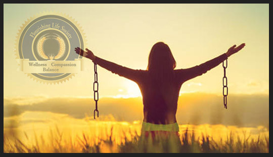 Person with broken chains on arms, standing in field, lifting arms toward beautiful sun. A Flourishing Life Society article on Self Forgiveness
