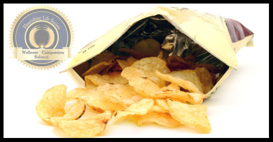 An open bag of potato chips spilling onto white background. A Flourishing Life Society article on ultra processed foods.
