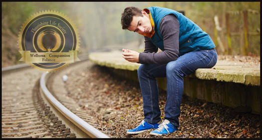 A young man sitting by RR tracks looking depressed. An article on bouncing back from life challenges